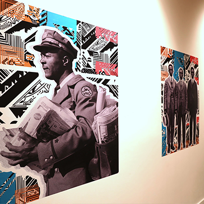 A white wall with two graphic artworks on it featuring black-and-white photos of African American men in suits, cropped and displayed against colorful, patterned backgrounds.