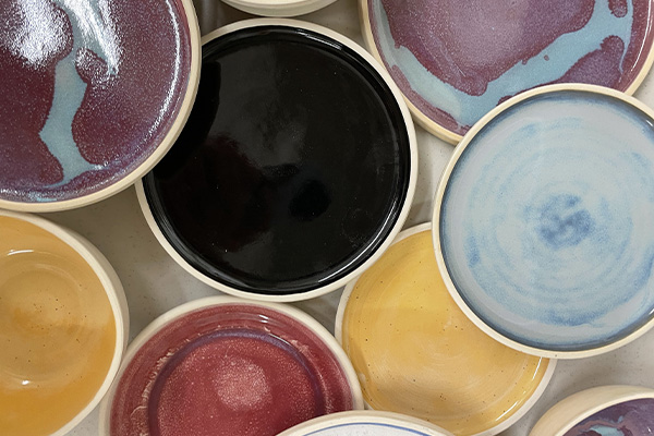 A collection of multi-colored clay or terra-cotta plates randomly placed in a composition.