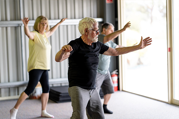 Adults do tai chi in a brightly-lit studio space.